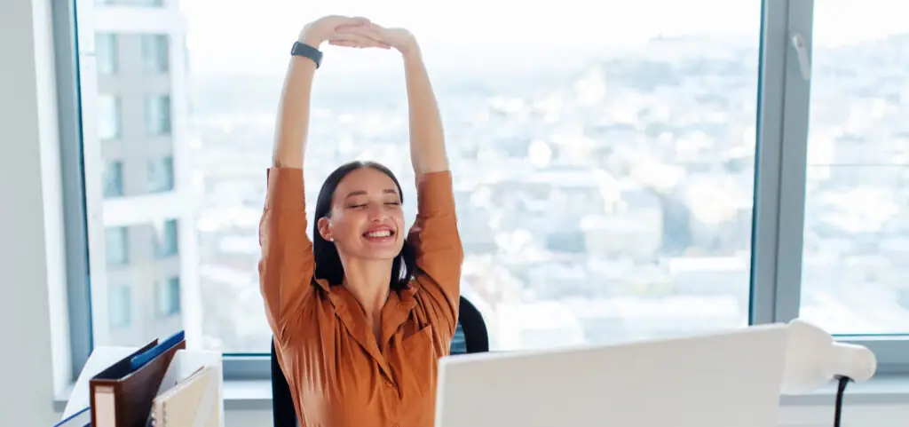 You have rights at work. An office worker stetches at her desk while smiling.