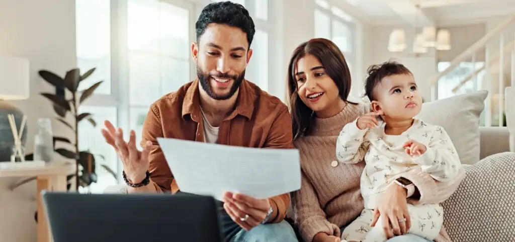 Un couple lit un document sur leur canapé pendant que leur enfant regarde ailleurs.