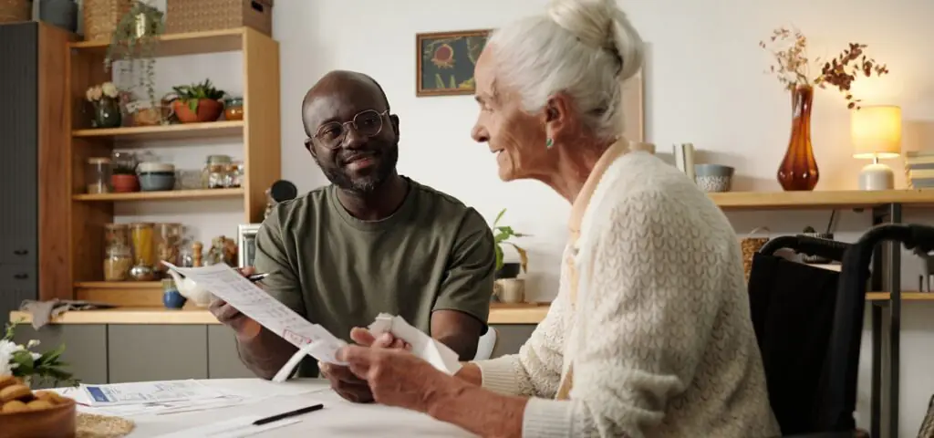 Un homme explique le contenu de documents à une personnes aînée en fauteuil roulant.