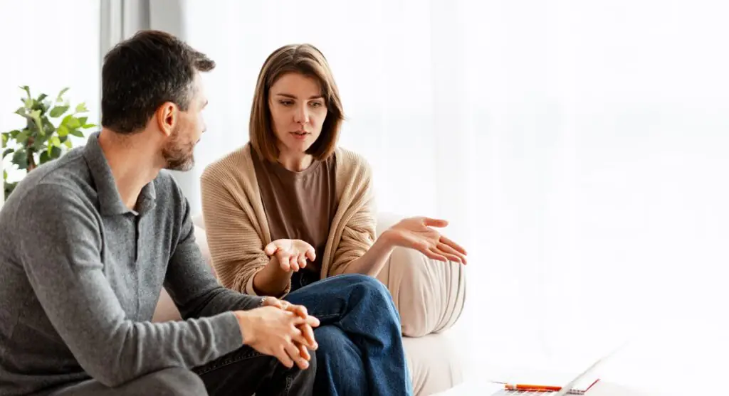 Couple assis sur un canapé, en train d’avoir une discussion.