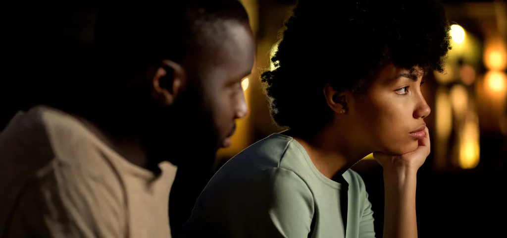 A couple sitting side by side, silent after a hard conversation.