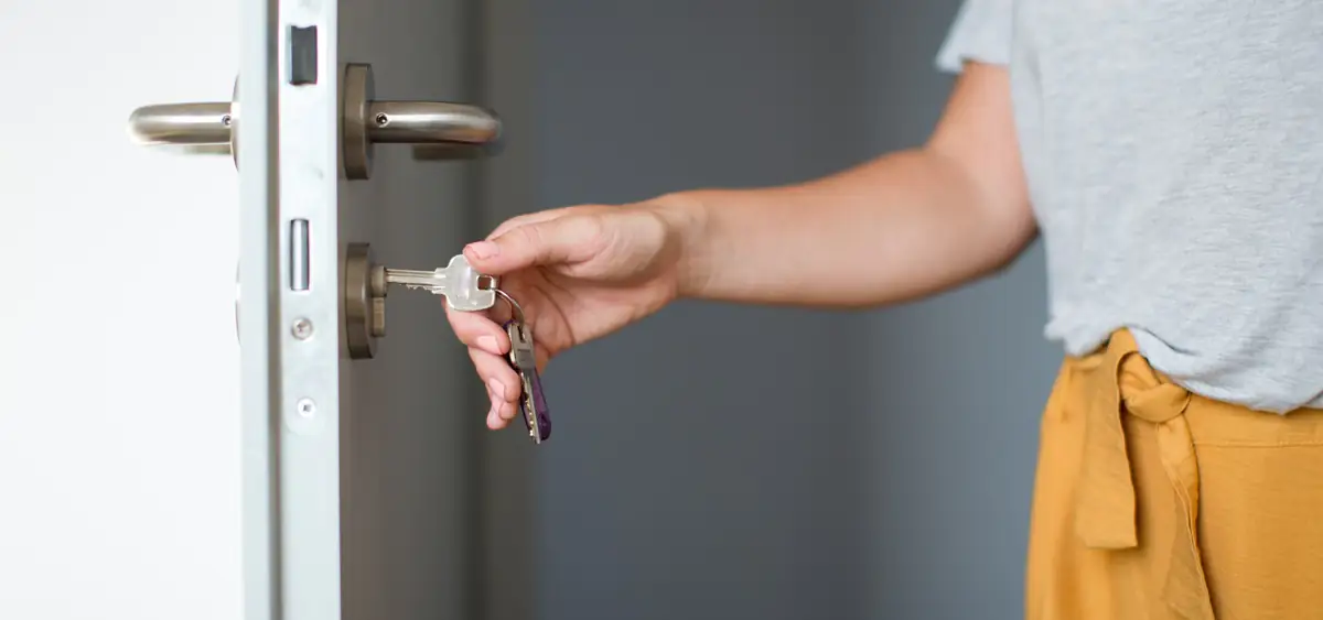 A woman uses keys to open a door.