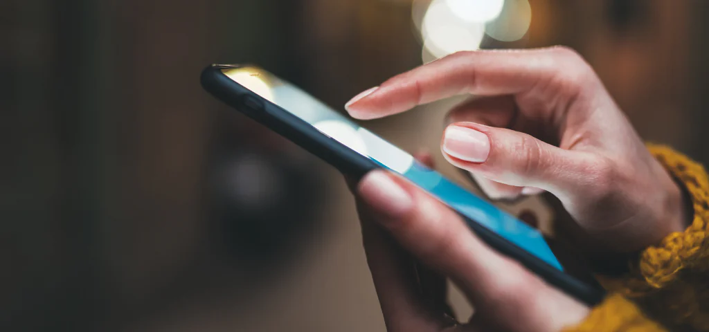 Une personne pointe du doigt quelque chose qu’elle semble avoir reçu sur son cellulaire.