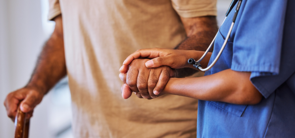 A nurse guiding a senior by holding his hand
