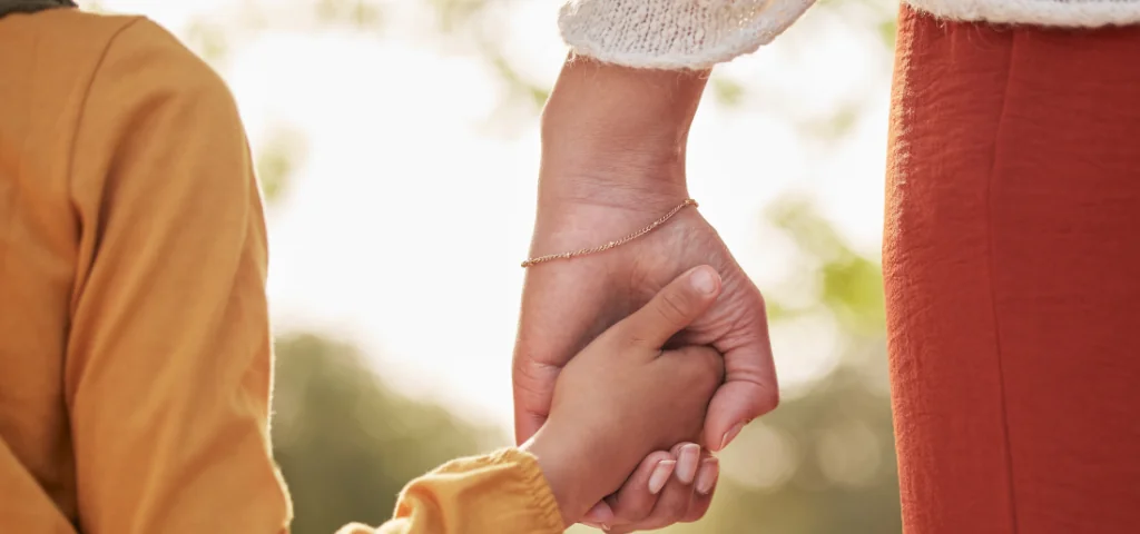 Un enfant et un adulte se tiennent par la main.