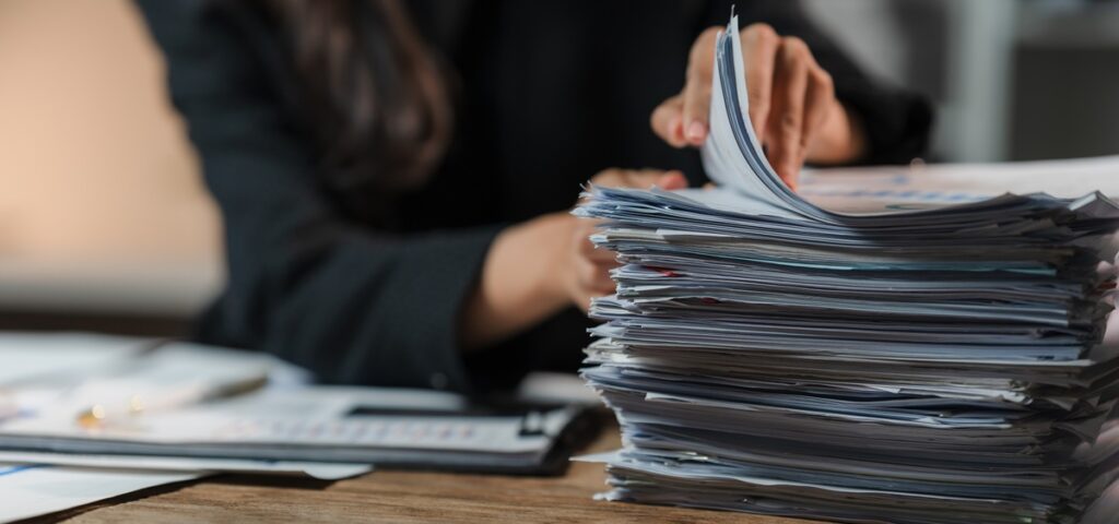 A woman examining a pile of documents.