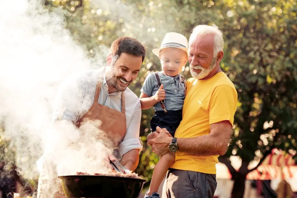 Peut-on se faire des grillades dans un parc? Un père, son fils et son beau-père font cuire de la nourriture sur un barbecue.