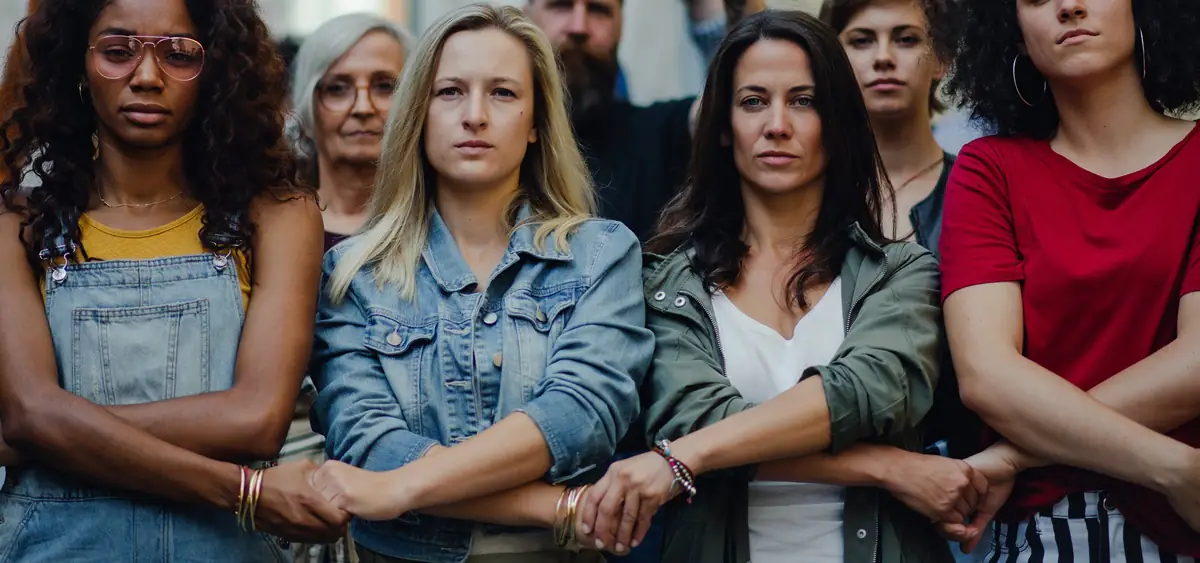 A group of women holding hands in the street during a protest. 