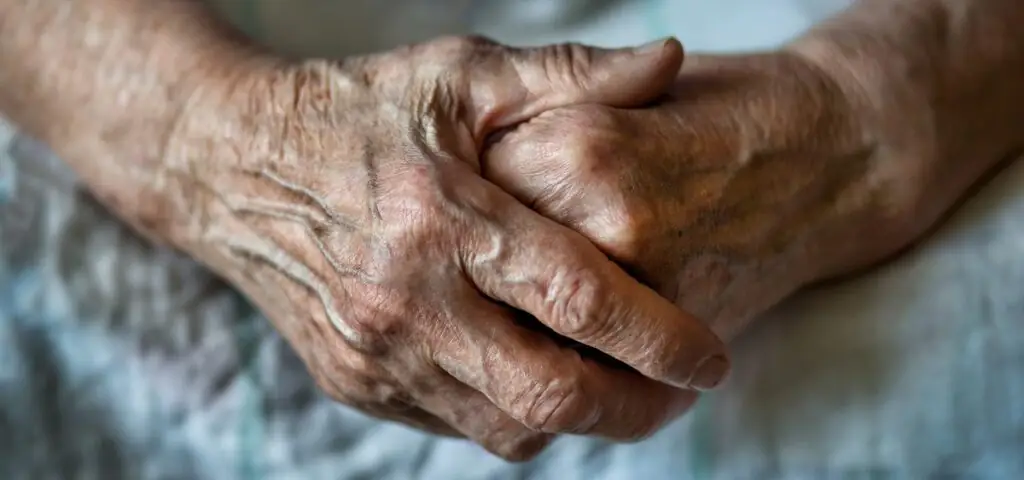 Taking advantage of a position of power at the expense of a vulnerable person’s interests is considered exploitation. Close up of an elderly woman’s hands, folded over each other.